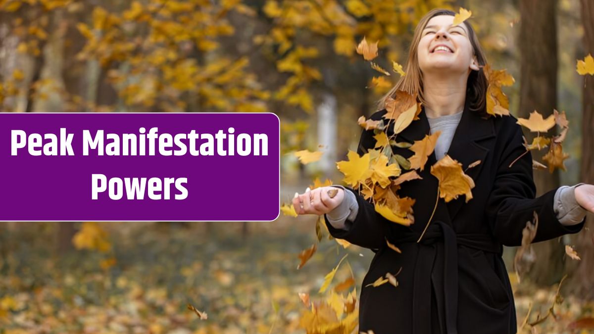 Happy young woman in a black coat in the forest among flying autumn leaves on a blurred background.