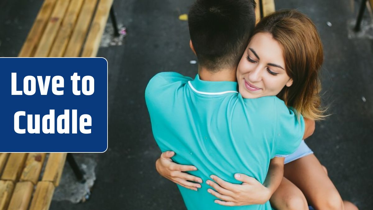 Girl and guy sitting on bench hugging.