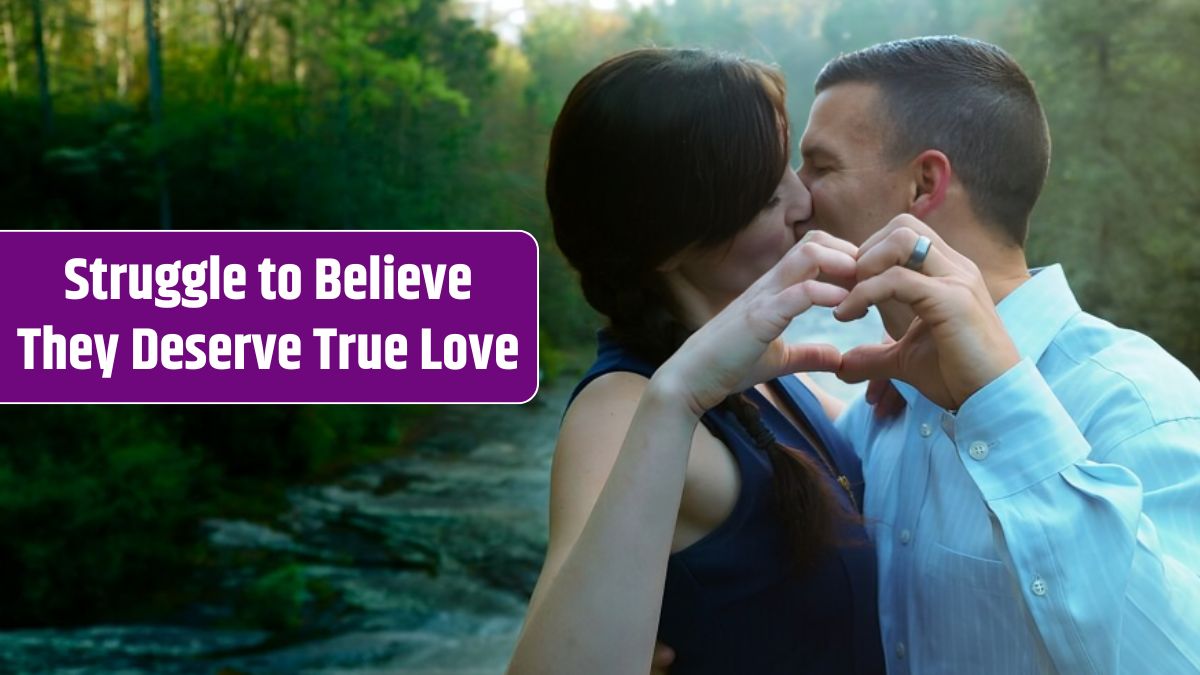 Couple kissing and doing the heart-shape with hands surrounded by greenery and a waterfall.